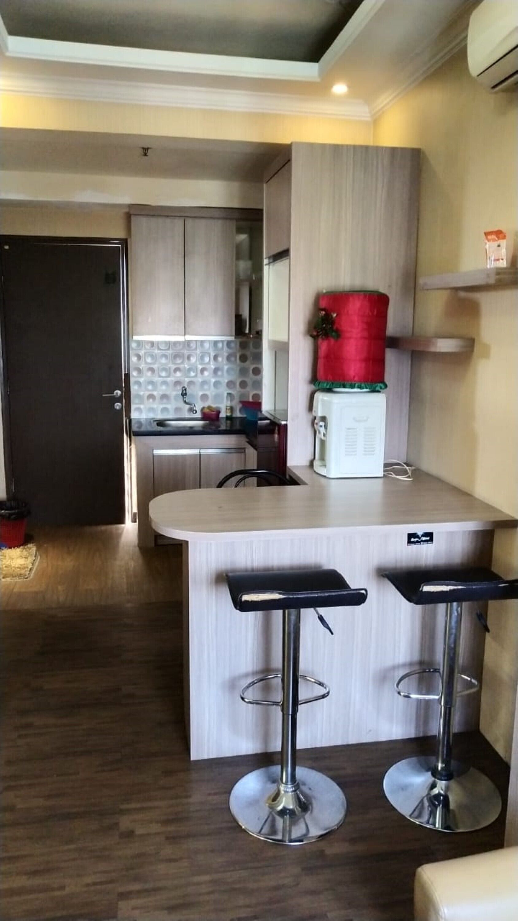 Una cocina moderna con una isla central, dos taburetes de bar, un refrigerador y un microondas.