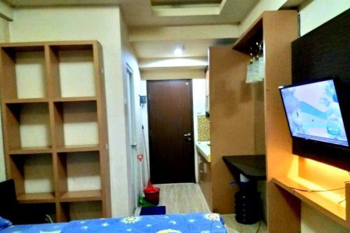 Un dormitorio con cama, televisión, escritorio y estanterías empotradas.