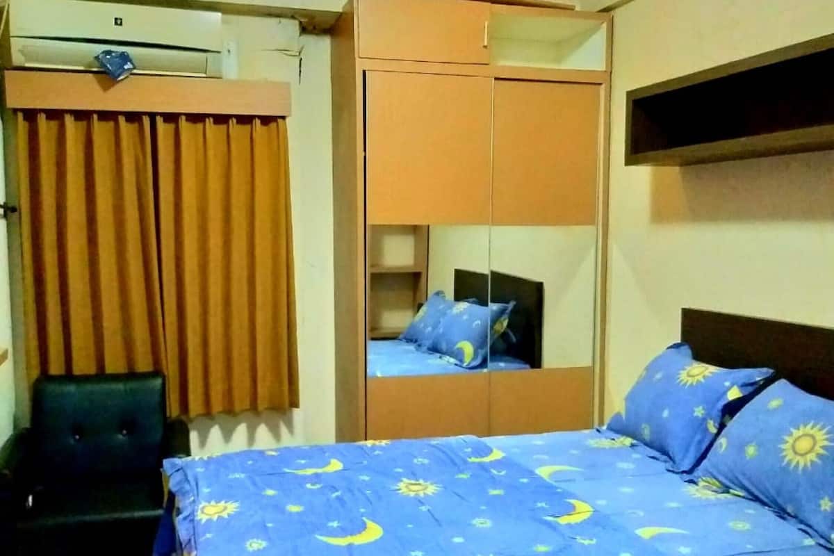 Un dormitorio con cama, armario, silla y espejo.