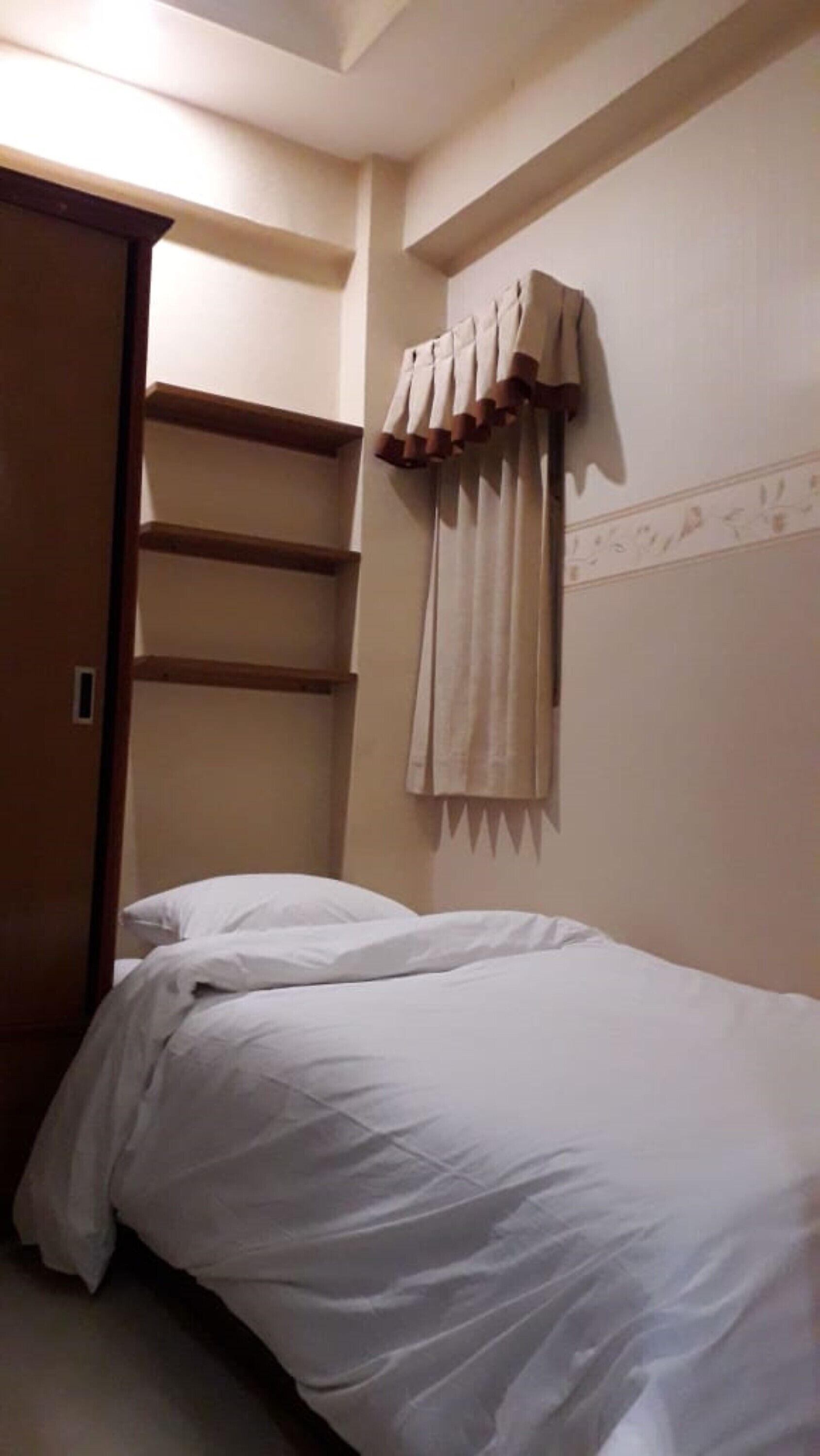 A bedroom with a bed, a wardrobe, and a curtain.