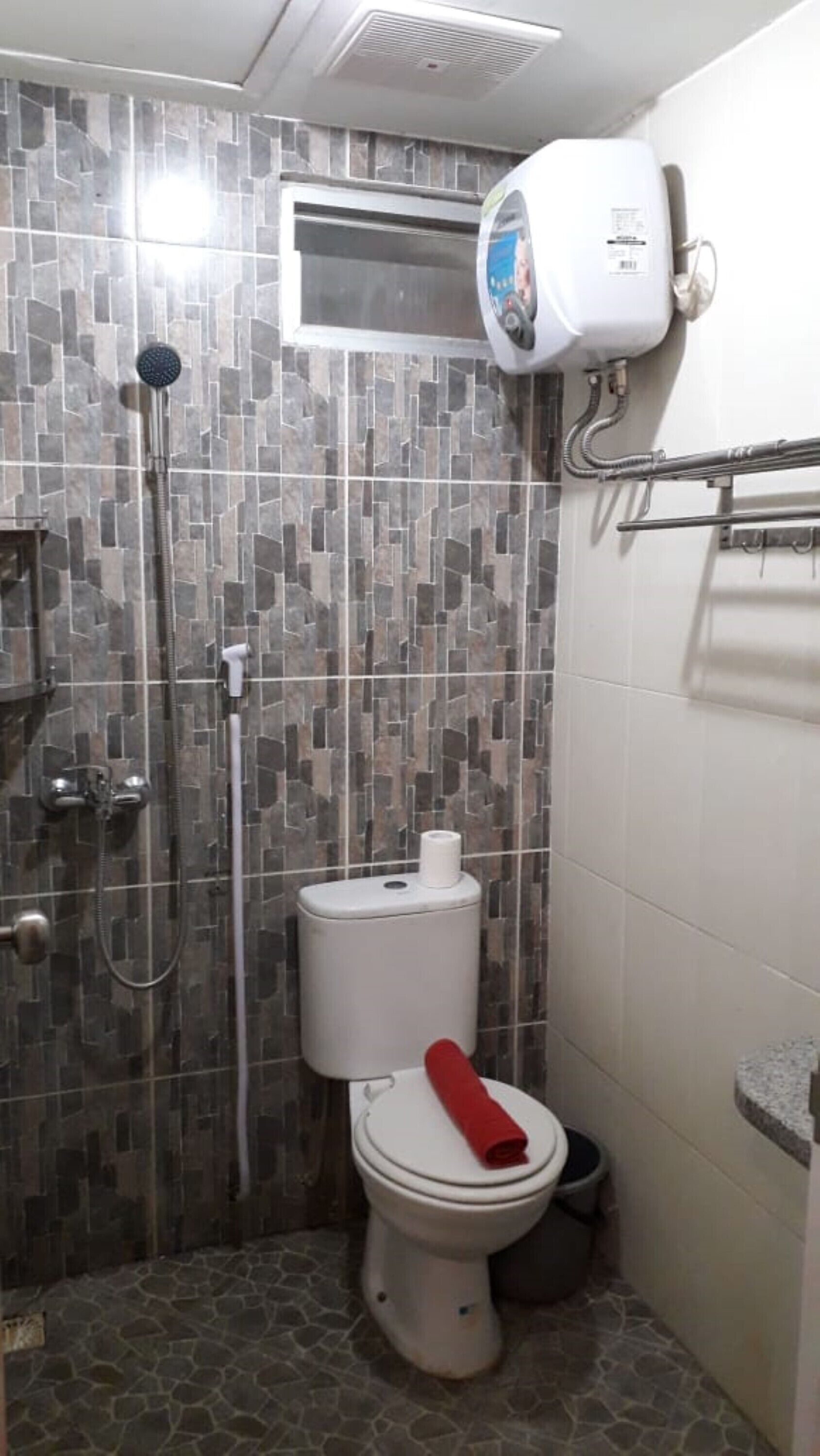 A small bathroom with a shower, toilet, and a towel rack.