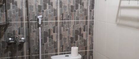 A small bathroom with a shower, toilet, and a towel rack.