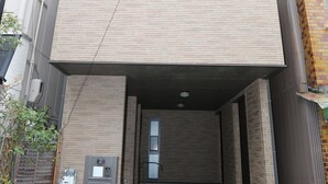 Een meerhoog gebouw met een overdekte ingang en een functionele doos op de begane grond.