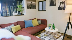 Een woonkamer met een hoekbank, een ronde salontafel en een kamerbreed tapijt met een patroon.