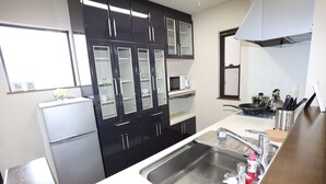 Een kleine keuken met een koelkast, magnetron, spoelbak en donkere kastjes.