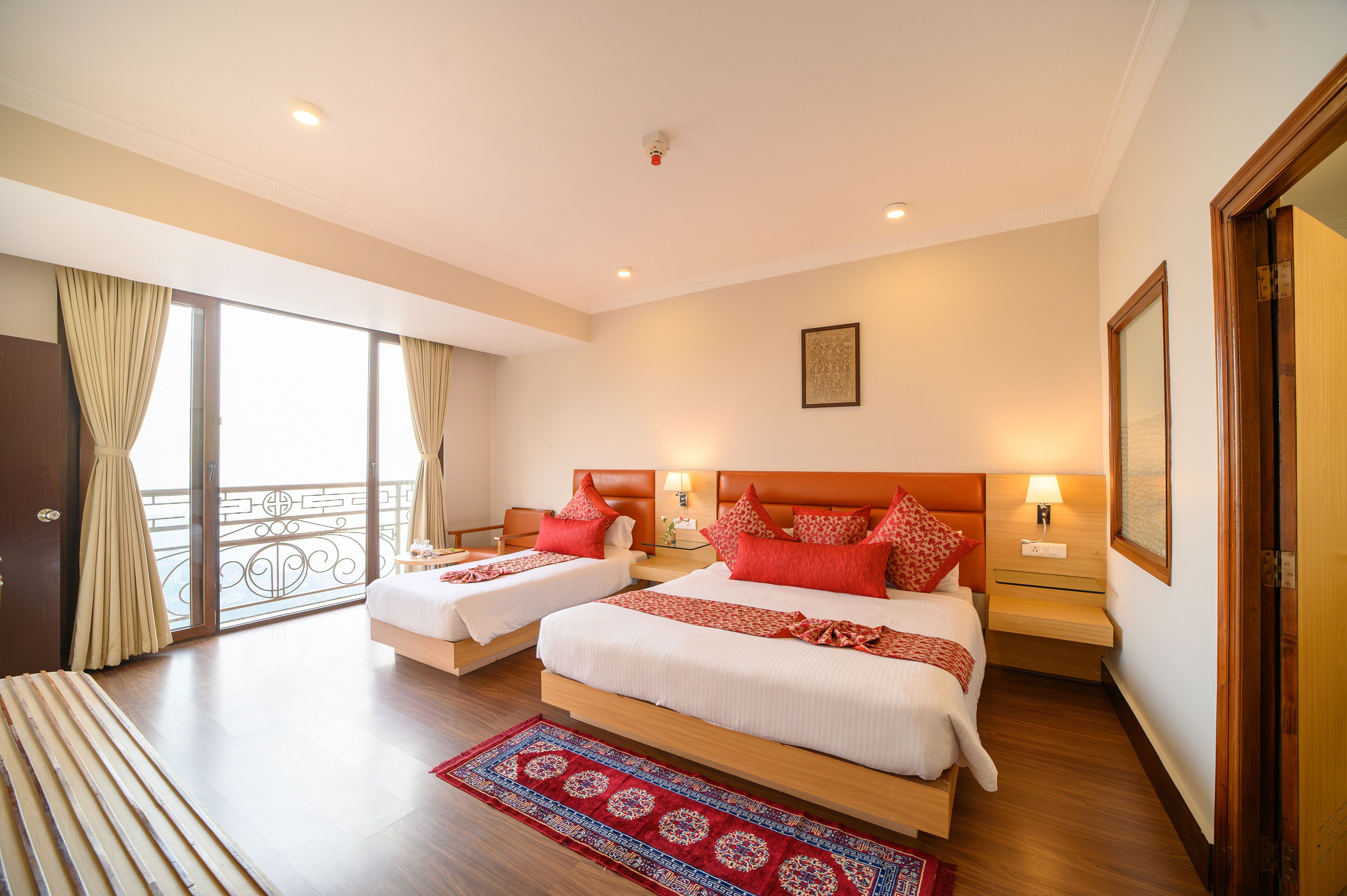 A hotel room with two beds, a balcony, and a large window.
