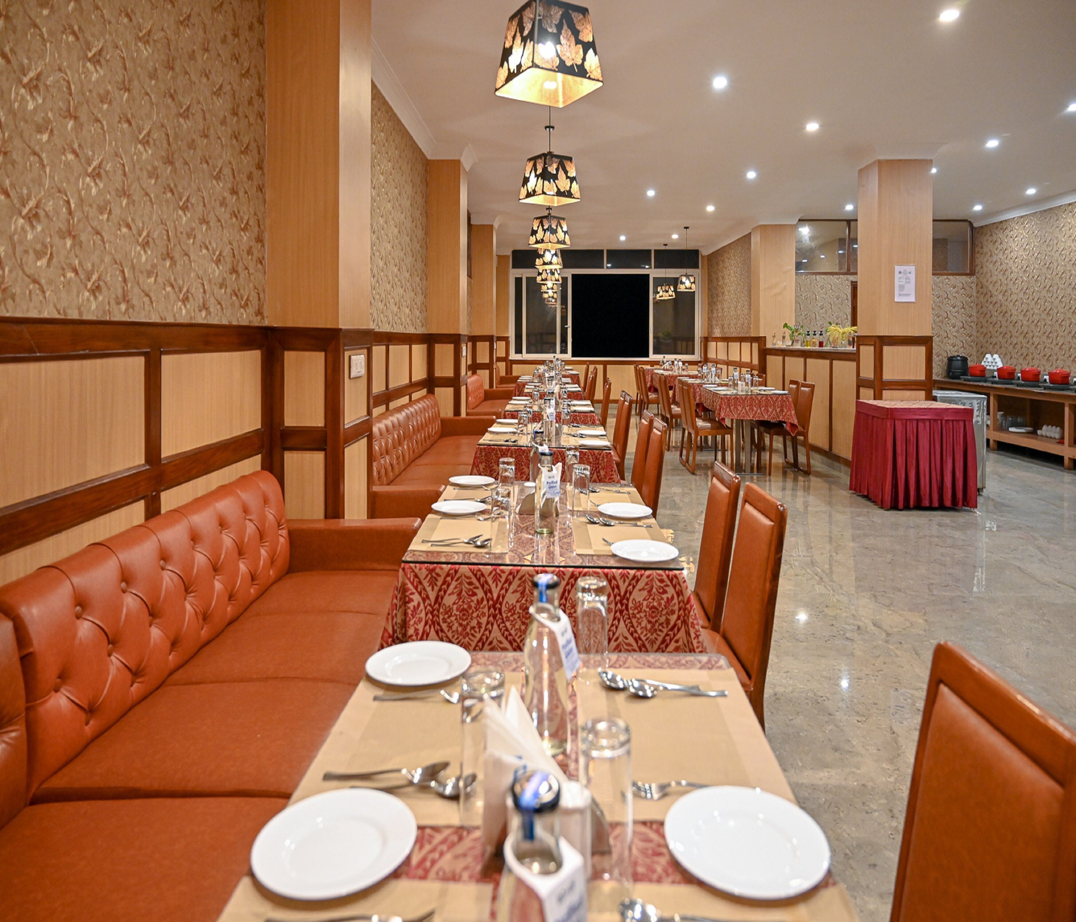 Ein Restaurant mit einem langen Esstisch, gedeckt für eine Mahlzeit, umgeben von Sitzecken und einzelnen Tischen.