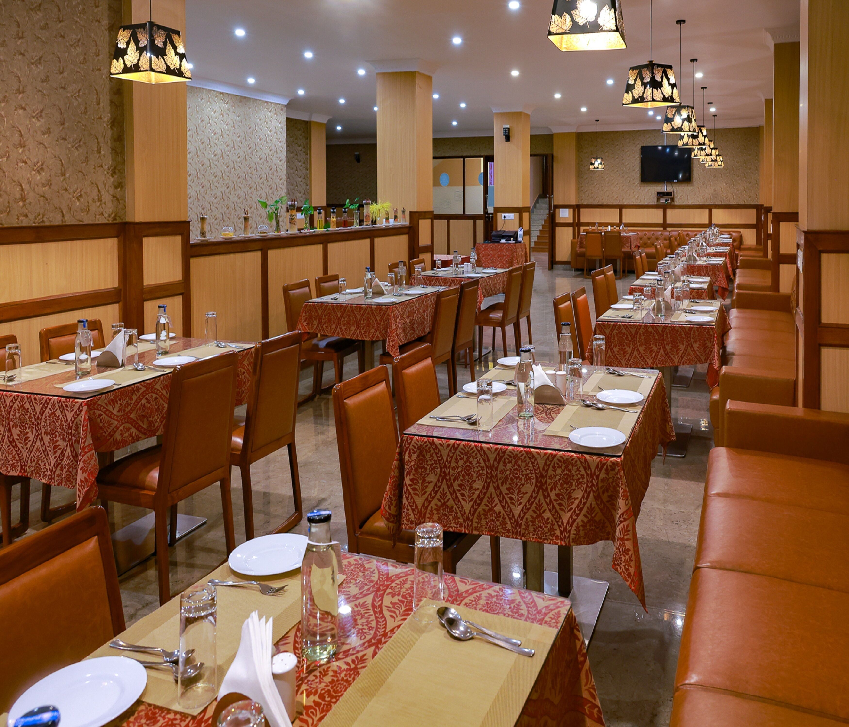 Un restaurante con varias mesas dispuestas para comer, cada una con sillas y cubiertos.