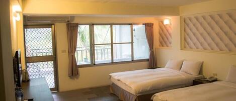 A hotel room with two beds, a small desk, a chair, and a window with curtains.