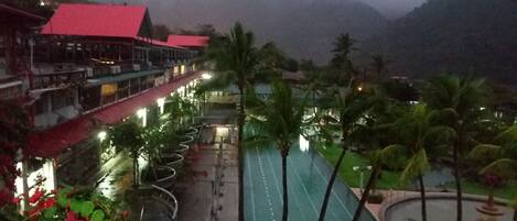 Un resort con piscina, palmeras y un edificio de techo rojo.