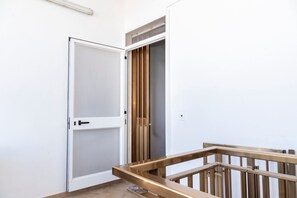 Ein Zimmer mit einer weißen Tür, einem Holgeländer und einem Fenster mit Jalousien.