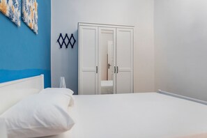 Ein Schlafzimmer mit einem Bett, einem Kleiderschrank und einer Wand mit blau-weißem Muster.