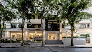 Een modern hotel met een gevel waarop de tekst 'SUWAN TOWER' en 'THE COTTON' staat.