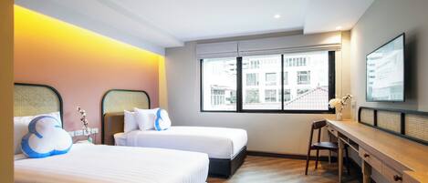 Habitación de hotel con dos camas, un escritorio y un amplio ventanal con vistas a la ciudad.