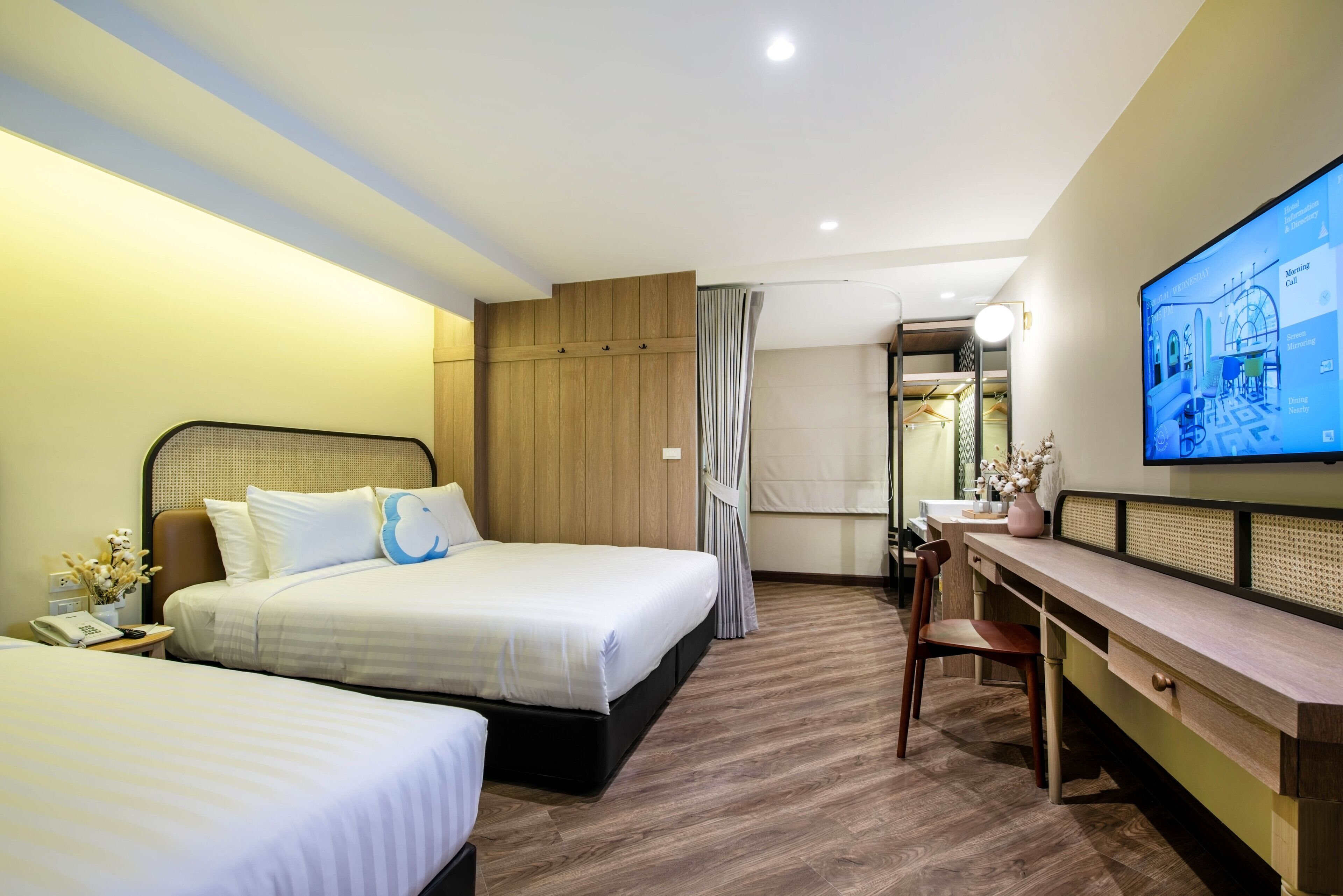 A hotel room with two beds, a desk, a chair, and a television displaying a hotel map.