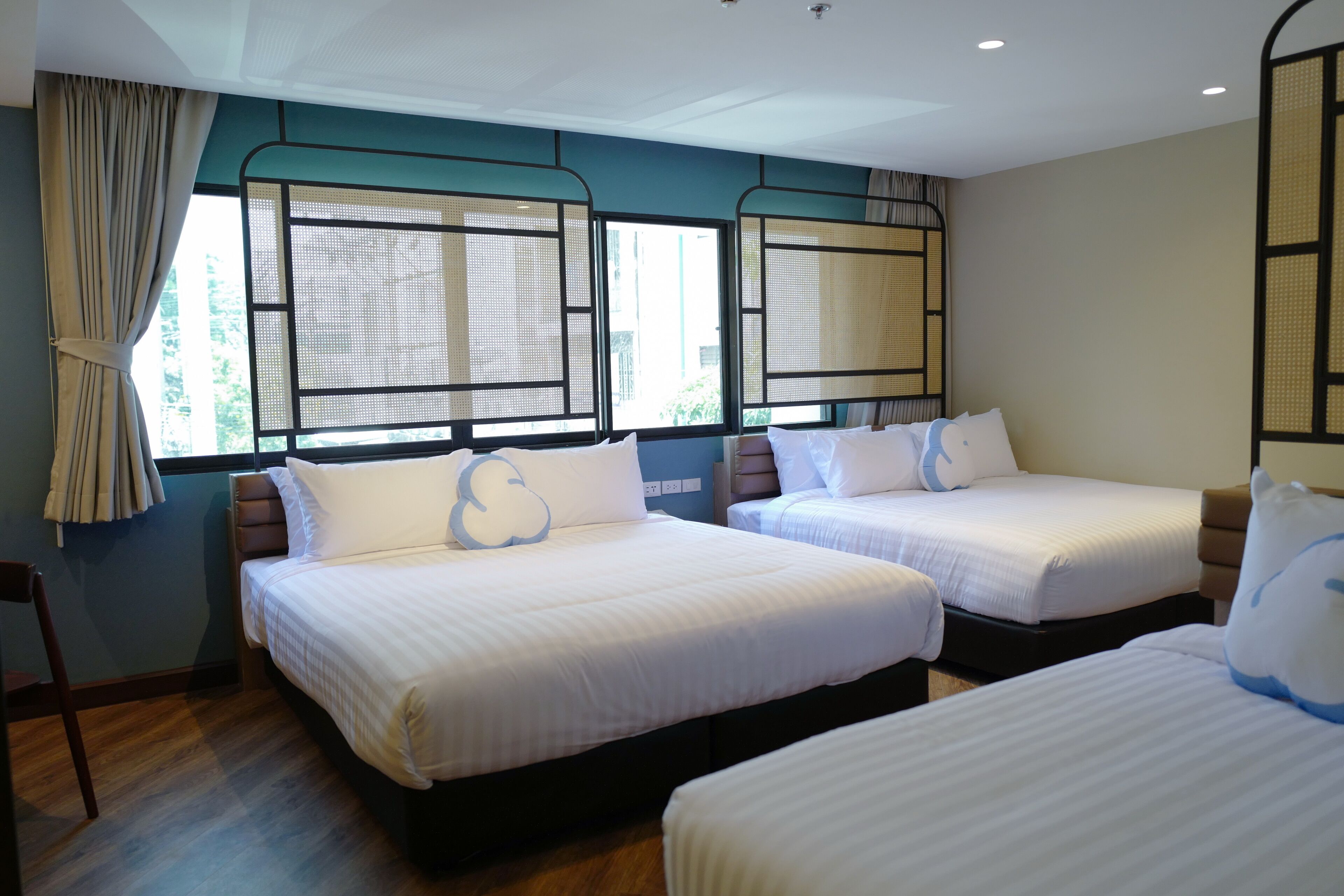 Quarto de hotel com duas camas de solteiro, uma janela grande com vista e cortina no lado esquerdo.