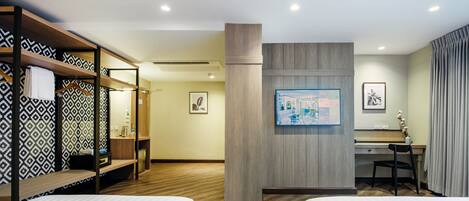 A hotel room with two beds, a desk, a chair, a wardrobe, and a wall-mounted TV.