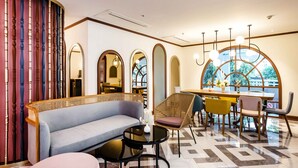 Een moderne hotel lobby met een ronde tafel, zithoek en grote ramen.