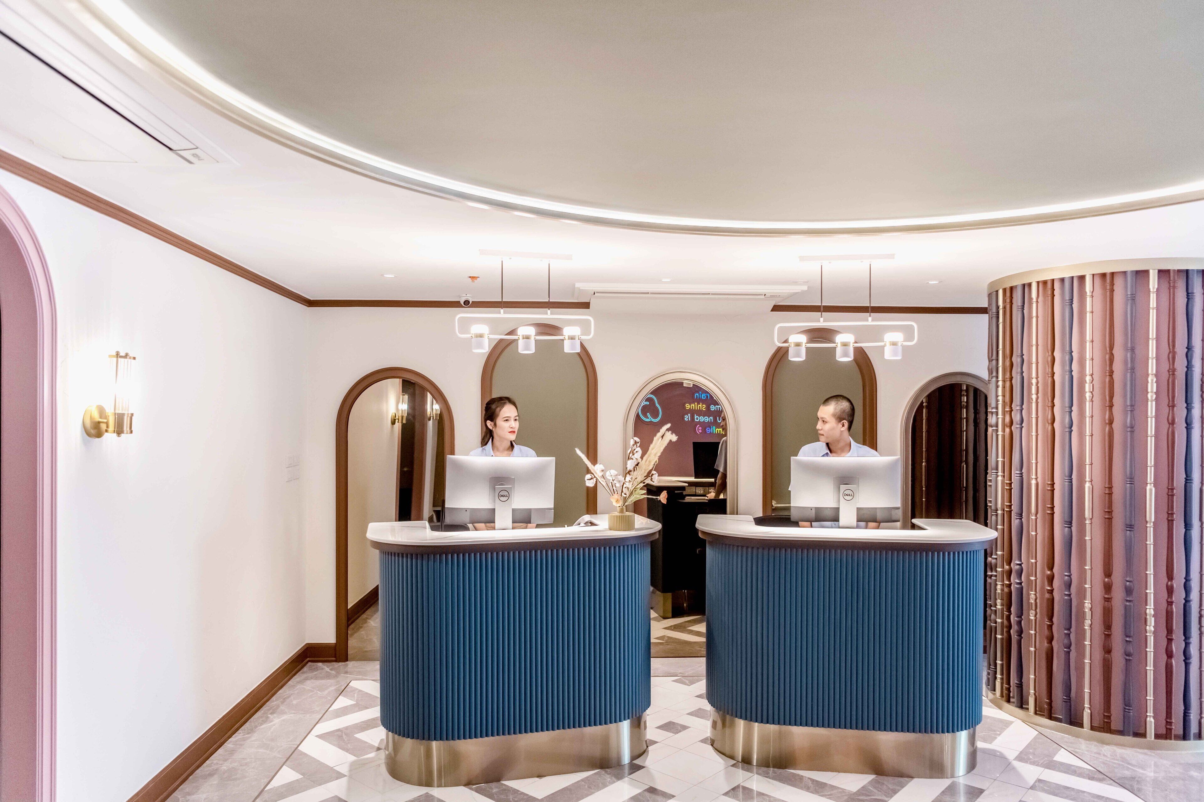 Een receptiezone met twee balies, een incheckruimte en een decoratieve wand met verticale panelen.