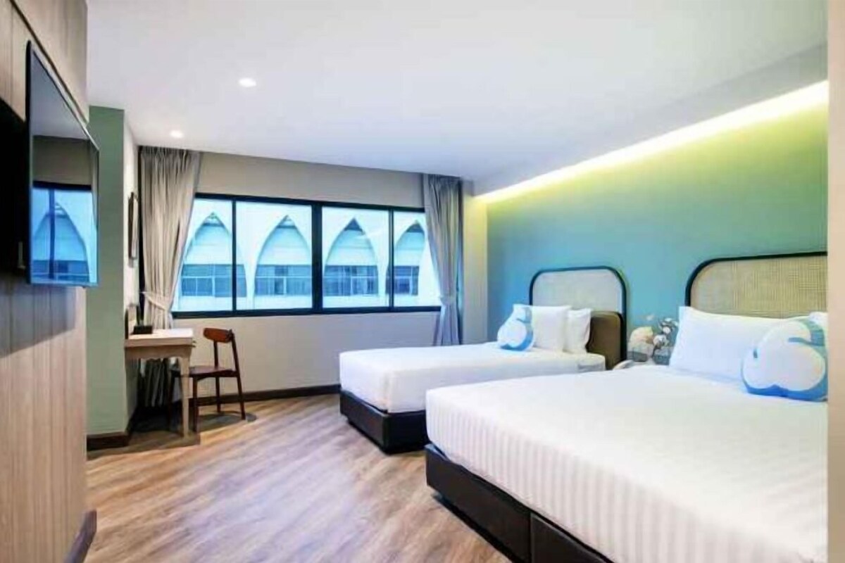 Une chambre d’hôtel avec deux lits, un bureau et une télévision.