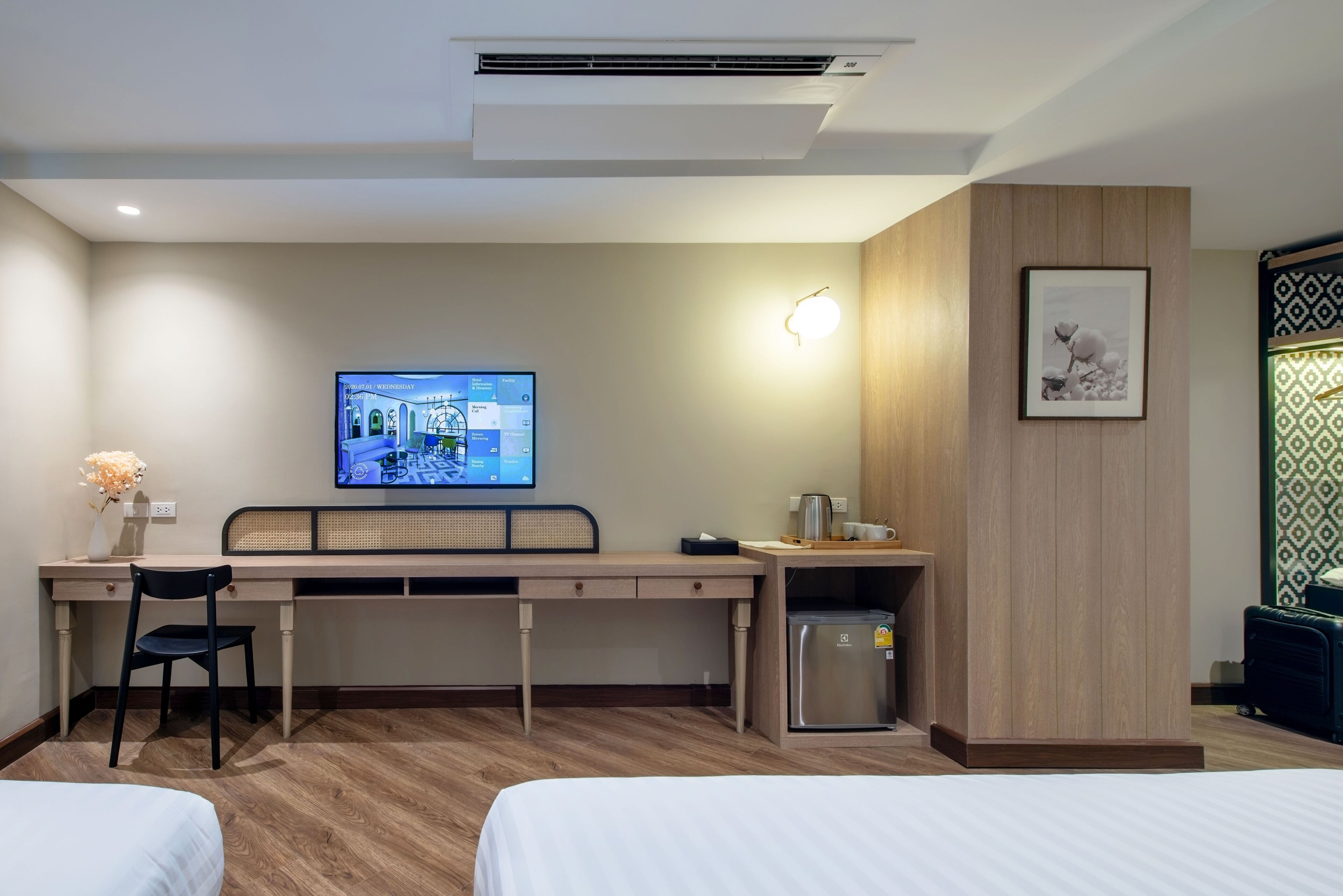 Ein Hotelzimmer mit einem Bett, einem Schreibtisch mit Stuhl, einem Fernseher, einem Kühlschrank und einer Wandleuchte.