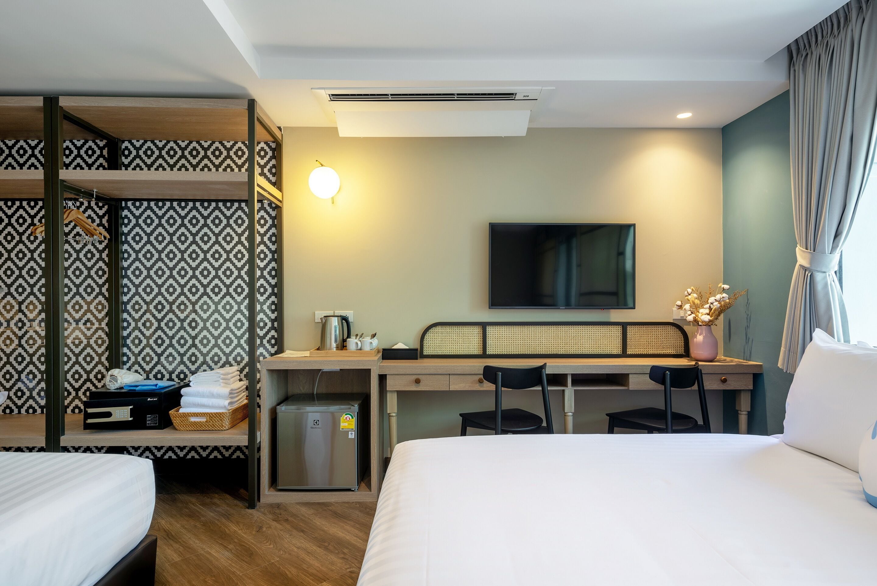 A hotel room with a bunk bed, a desk with a chair, a television, and a small kitchenette.