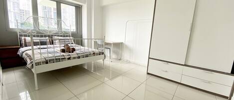 A modern bedroom with a metal bed frame, a large window, and a wardrobe.