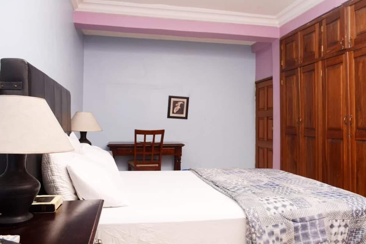 Une chambre à coucher comprenant un lit, des lampes de chevet, une chaise, un bureau et une armoire.