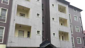 Um edifício com vários andares, varandas, janelas amplas e aparelhos de ar condicionado.