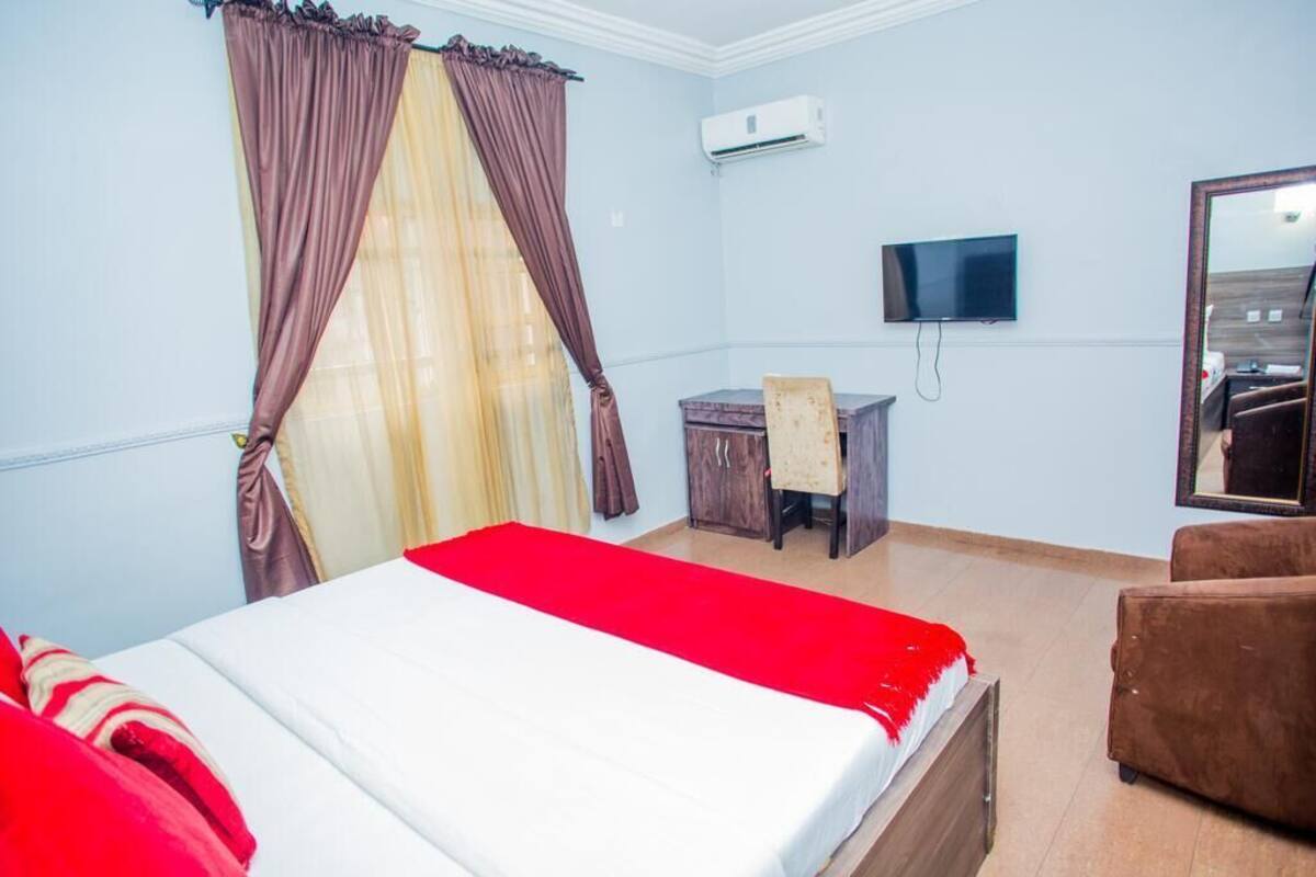 A hotel room with a bed, a desk, a chair, a TV, and a mirror.