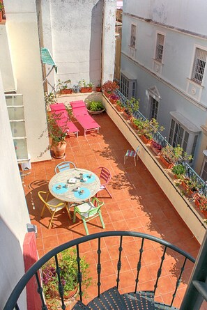 A rooftop terrace with a round table and chairs, potted plants, and a railing. - PENTHOUSE WITH LARGE TERRACE IN CENTRAL CENTER OF CÁDIZ (Cádiz)