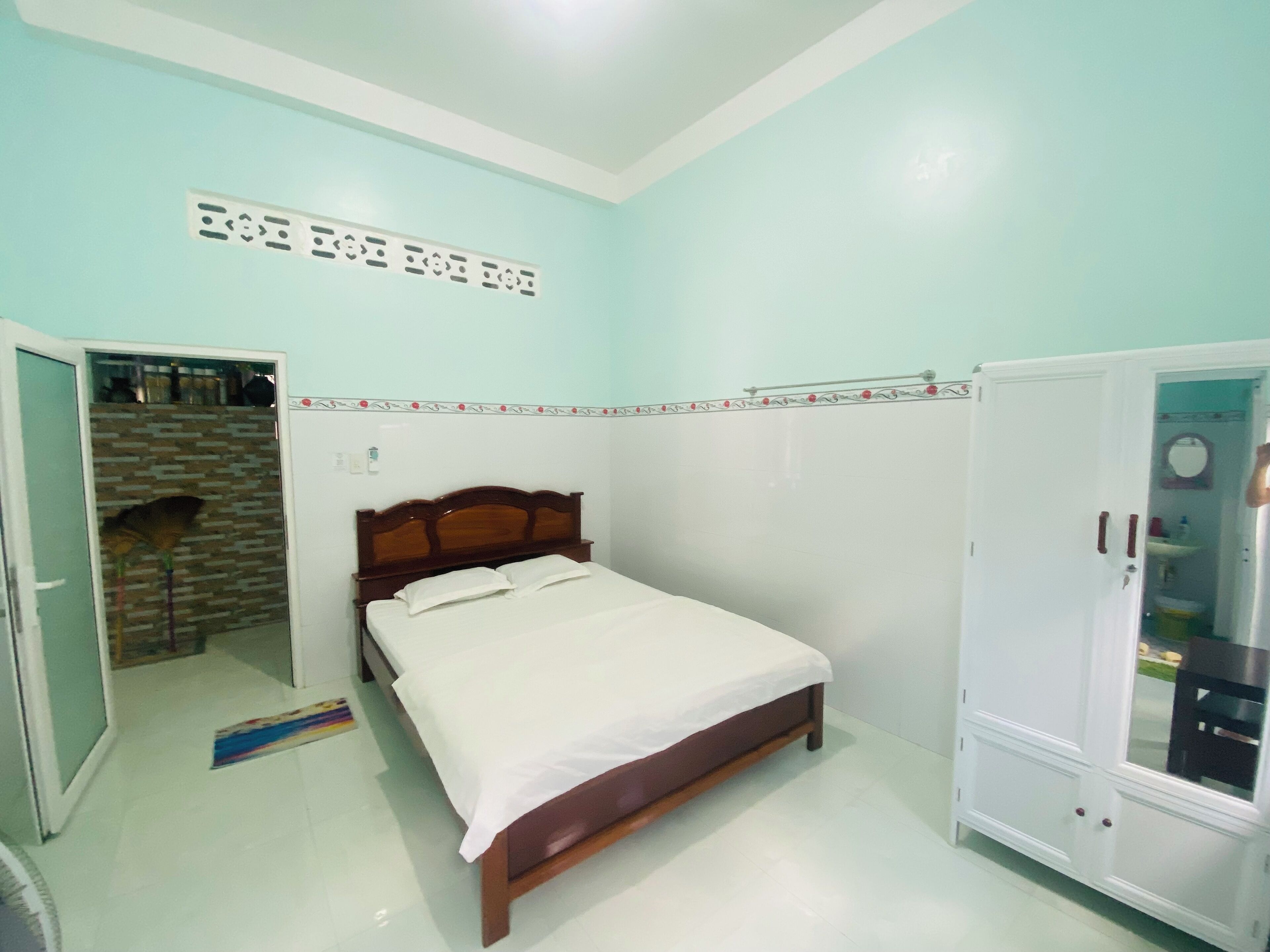 A bedroom with a bed, a wardrobe, and a bathroom visible through an open door.
