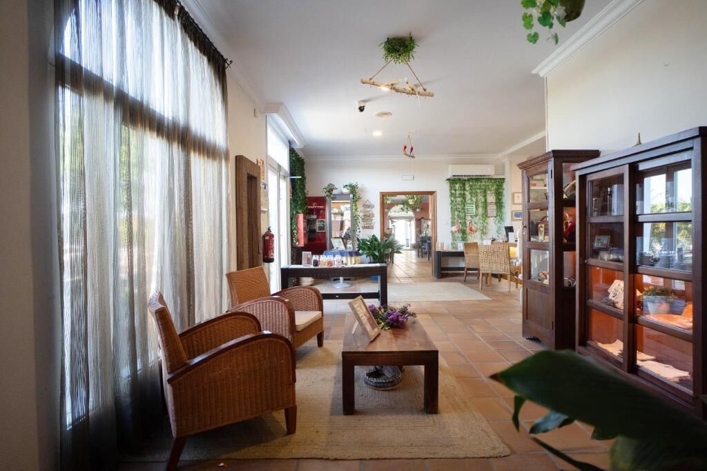 Eine Hotelhalle mit Korbmöbeln, einem Couchtisch und einer Glastheke.