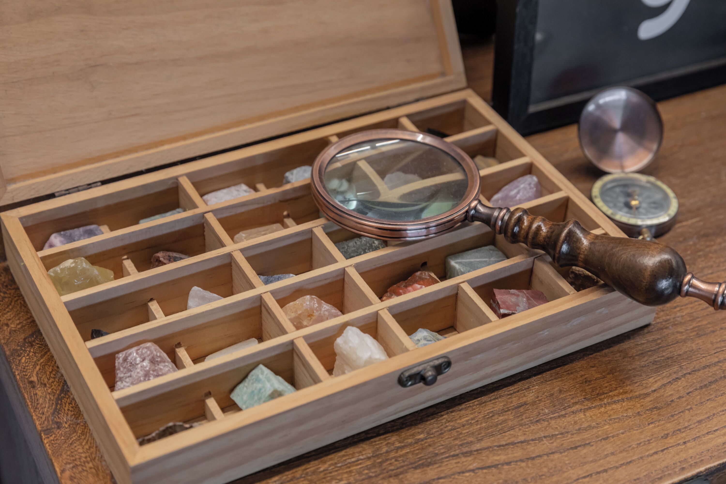Una caja de madera con compartimentos que contienen varios cristales y una lupa.