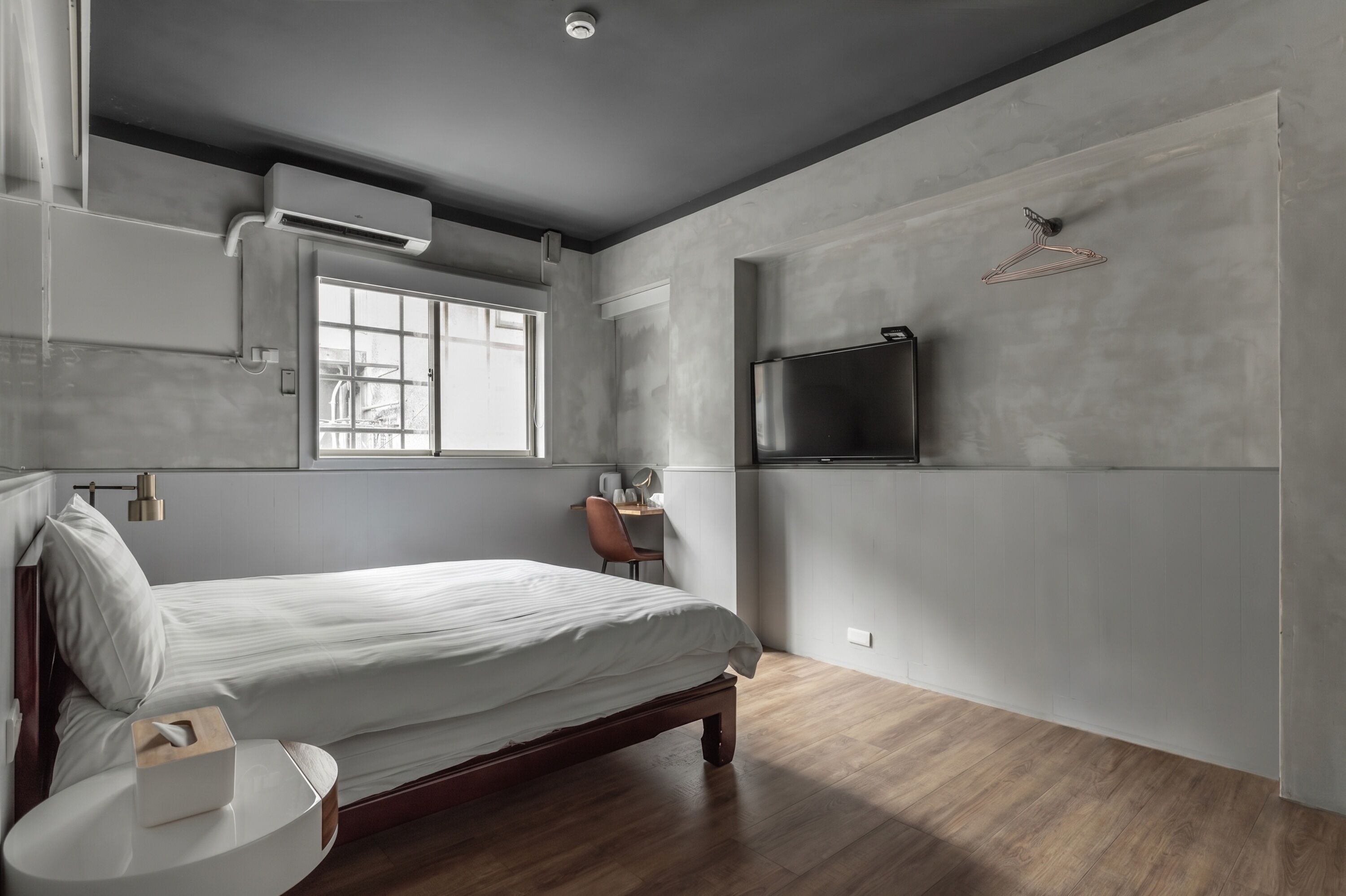 A bedroom with a bed, bedside table, and a TV mounted on the wall.