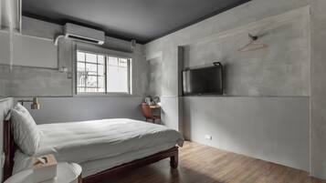 A bedroom with a bed, bedside table, and a TV mounted on the wall.