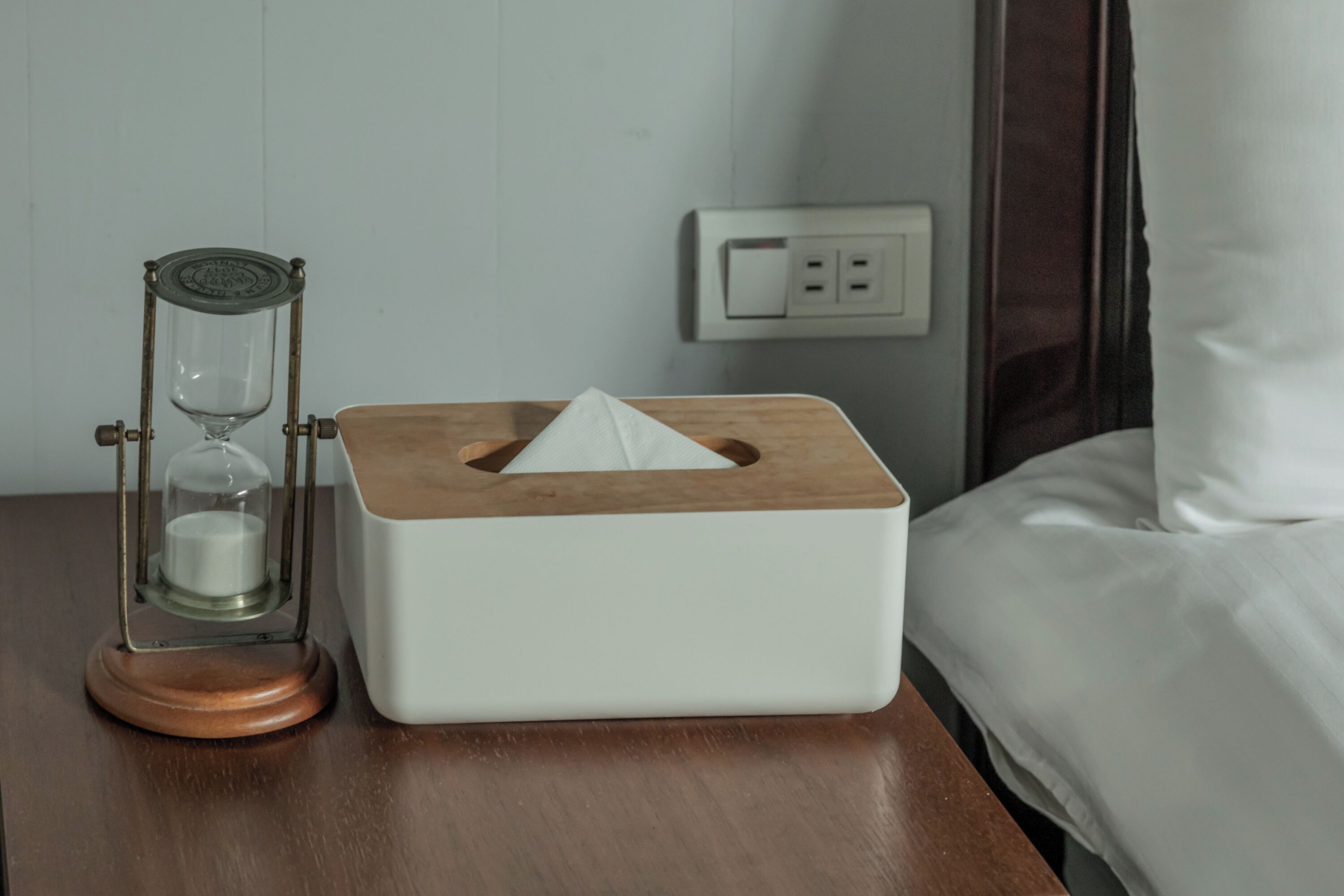 A bedside table with a tissue box and an hourglass.