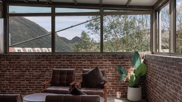 A sunlit room with brick walls, large windows, and leather chairs.