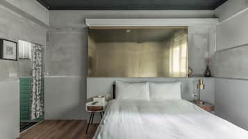 A bedroom with a large bed, a bedside table with a lamp, a green wall unit, and a window with curtains.