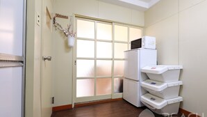 A small kitchen with a refrigerator, microwave, and stacked storage bins. - Pebliss Kurenai No.2 (Tokyo)
