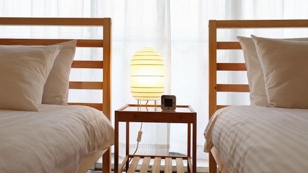 A hotel room with two wooden beds, a bedside table with a lamp, and sheer curtains. - Pebliss Kurenai No.2 (Tokyo)
