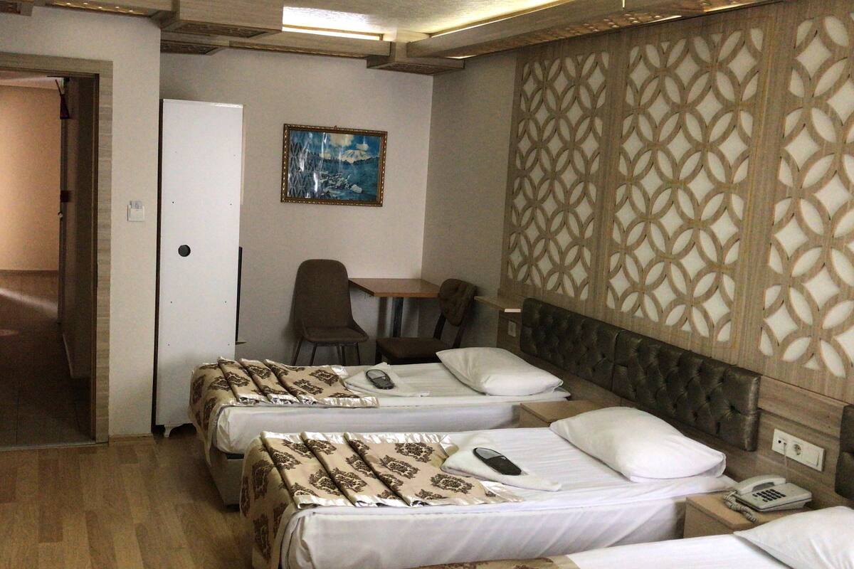 A hotel room with two beds, a desk, a chair, and a painting on the wall.