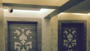 Duas portas com desenhos detalhados, numeradas 302 e 301, em um corredor com parede lisa e uma luminária no teto.