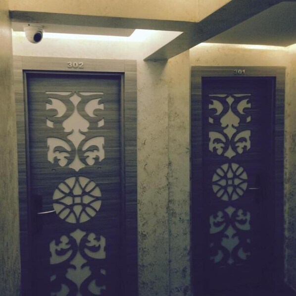 Dos puertas con diseños intrincados, con los números 302 y 301, en un pasillo con una pared lisa y una lámpara en el techo.