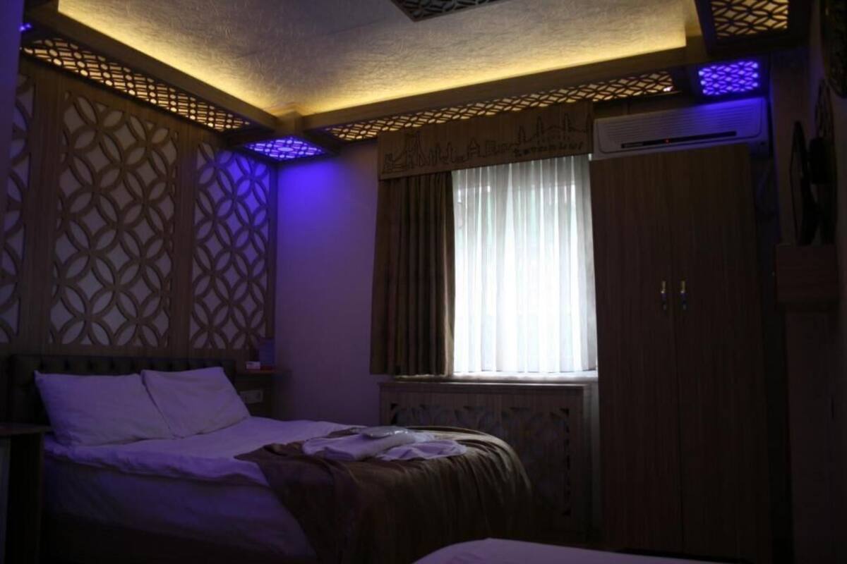 A bedroom with a bed, a window with curtains, a wardrobe, and a decorative ceiling.