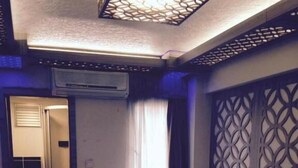 Quarto de hotel com duas camas, banheiro e um painel decorativo na parede.
