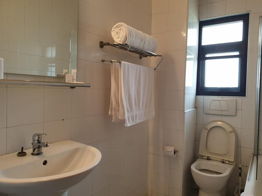 A bathroom with a sink, toilet, and towel rack.