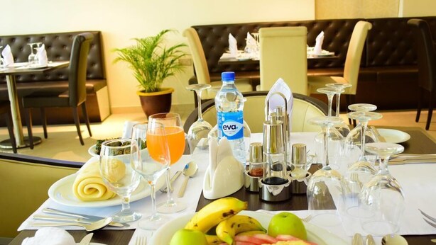 Een eettafel gedekt met een fruitschaal, een waterfles en verschillende glazen.