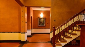 Un pasillo con una escalera, un cuadro en la pared y una lámpara colgante.