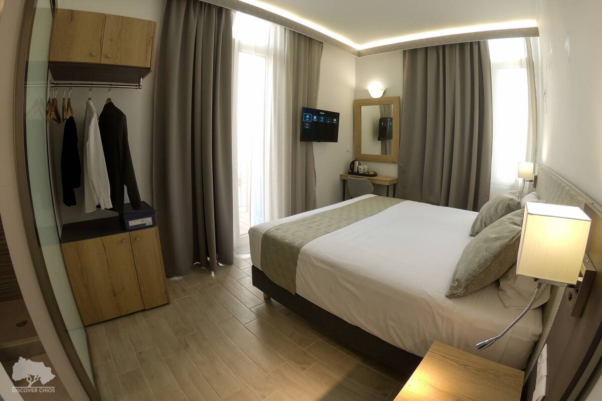 Una habitación de hotel con una cama, un escritorio, un televisor y un armario.